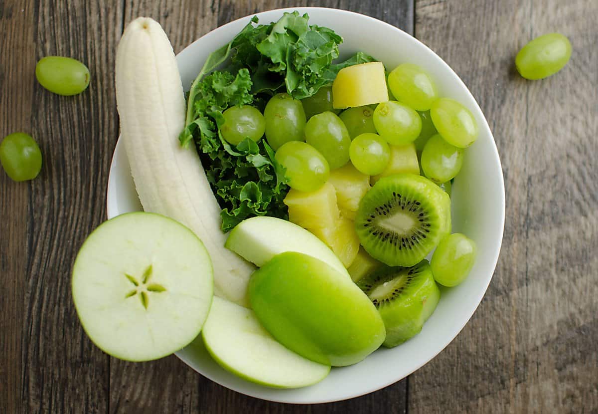 Ingredients for green smoothie: banana, green apple, green grapes, kale, pineapple, and kiwi.