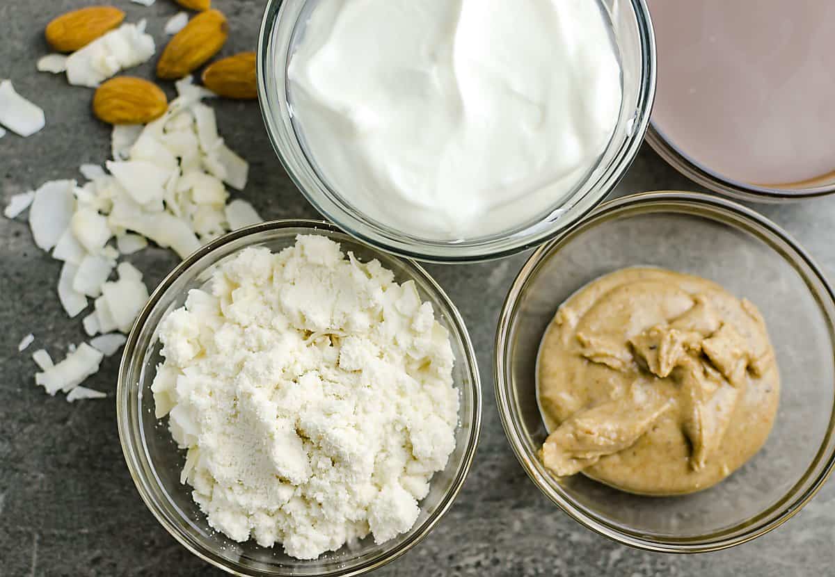 ingredients for almond joy smoothie: Yogurt, chocolate almond milk, whey protein powder, almond butter, coconut, almonds.