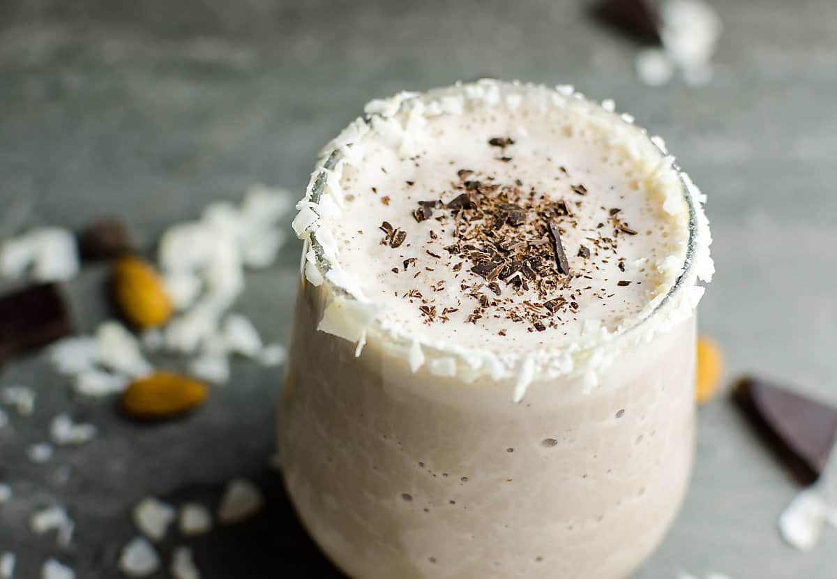 Healthy Almond Joy smoothie garnished with coconut chips and shaved dark chocolate.