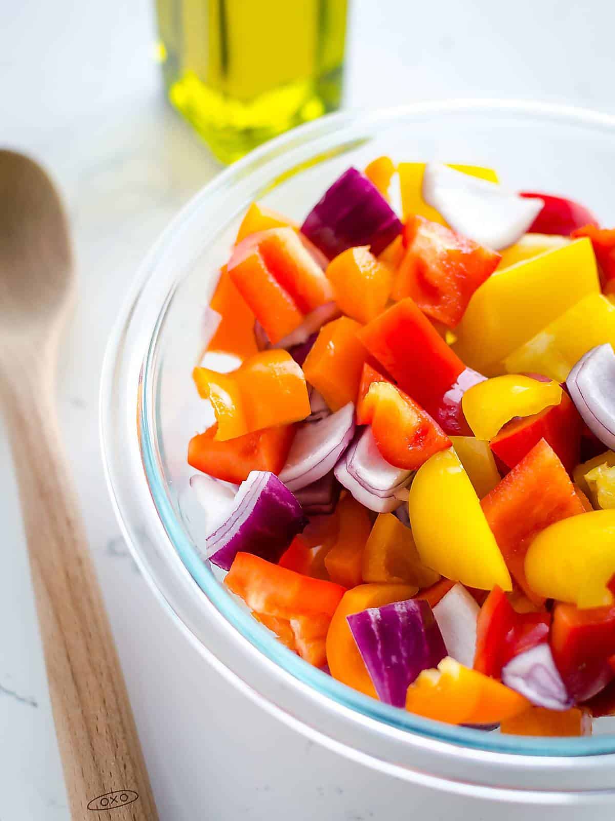 bowl of uncooked chopped colored bell peppers and red onion.