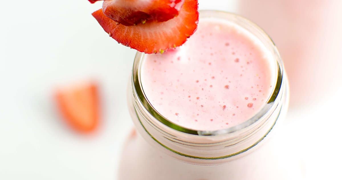 strawberry cheesecake smoothie in a glass garnished with strawberries.
