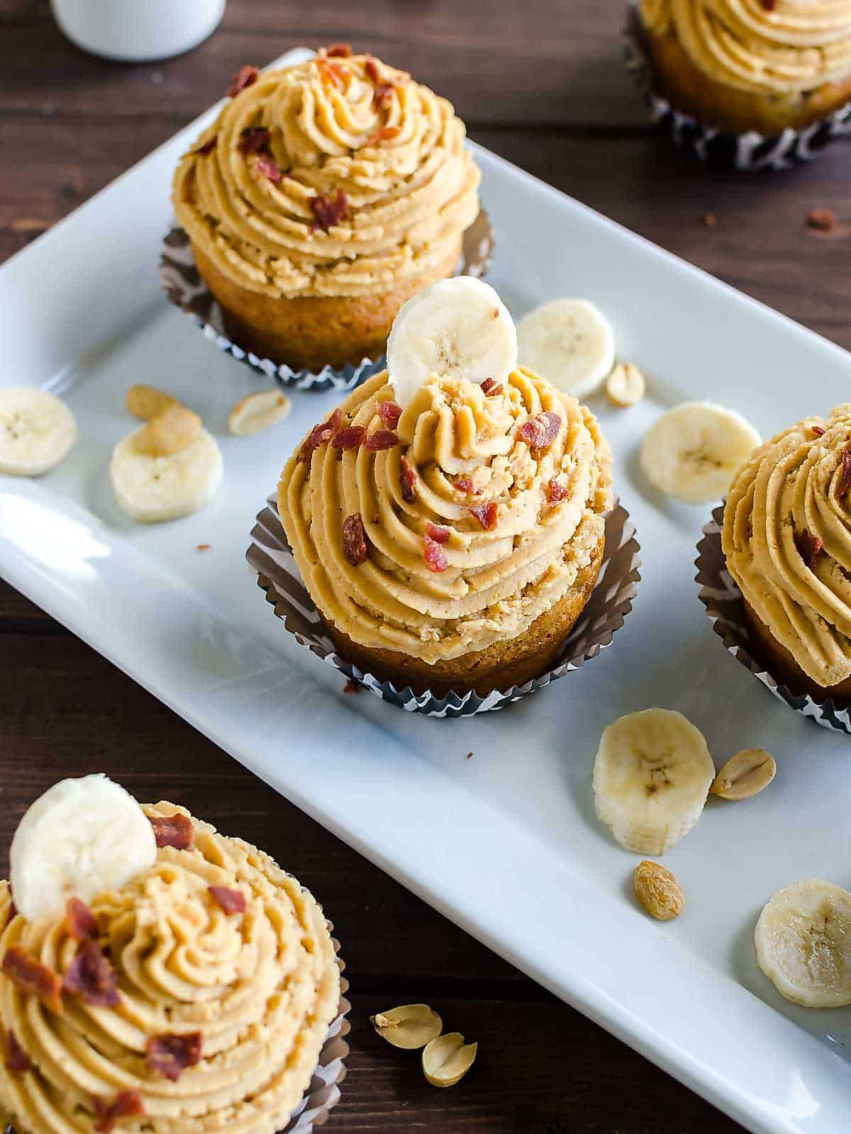 banana cupcake peanut butter frosting and bacon crumbles on a platter.