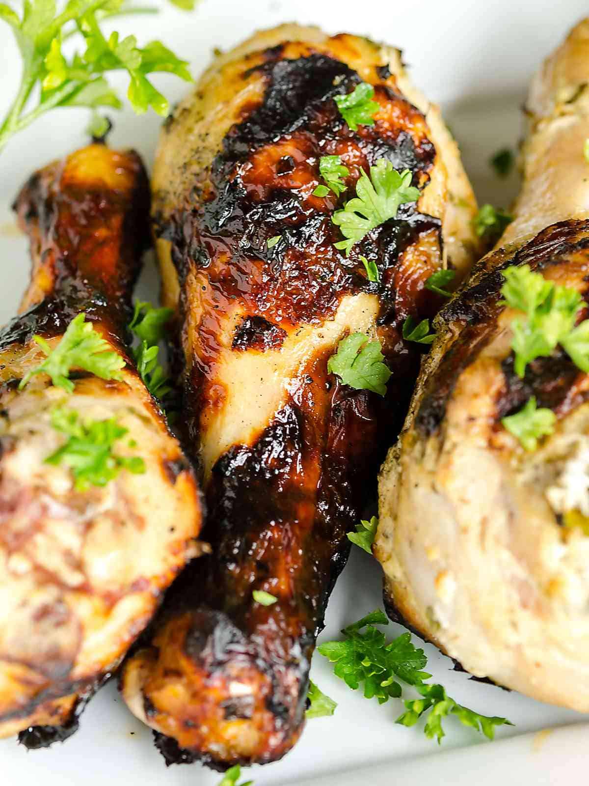 grilled chicken legs glistening in sauce, nicely charred from the grill.