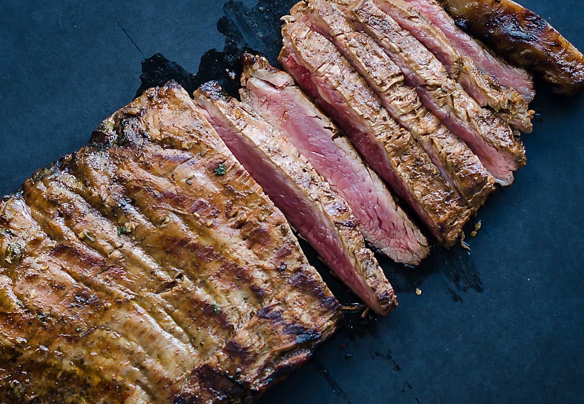 carne asada sliced thinly on a cutting board, meat is medium rare.