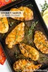 grilled chicken on a sheet pan with an orange colored sauce and fresh thyme.