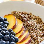 quinoa blueberries and peaches in a shallow white bowl, a row of each.