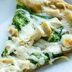 slice of hot homemade white pizza, melty cheese, chunks of chicken and spinach leaves