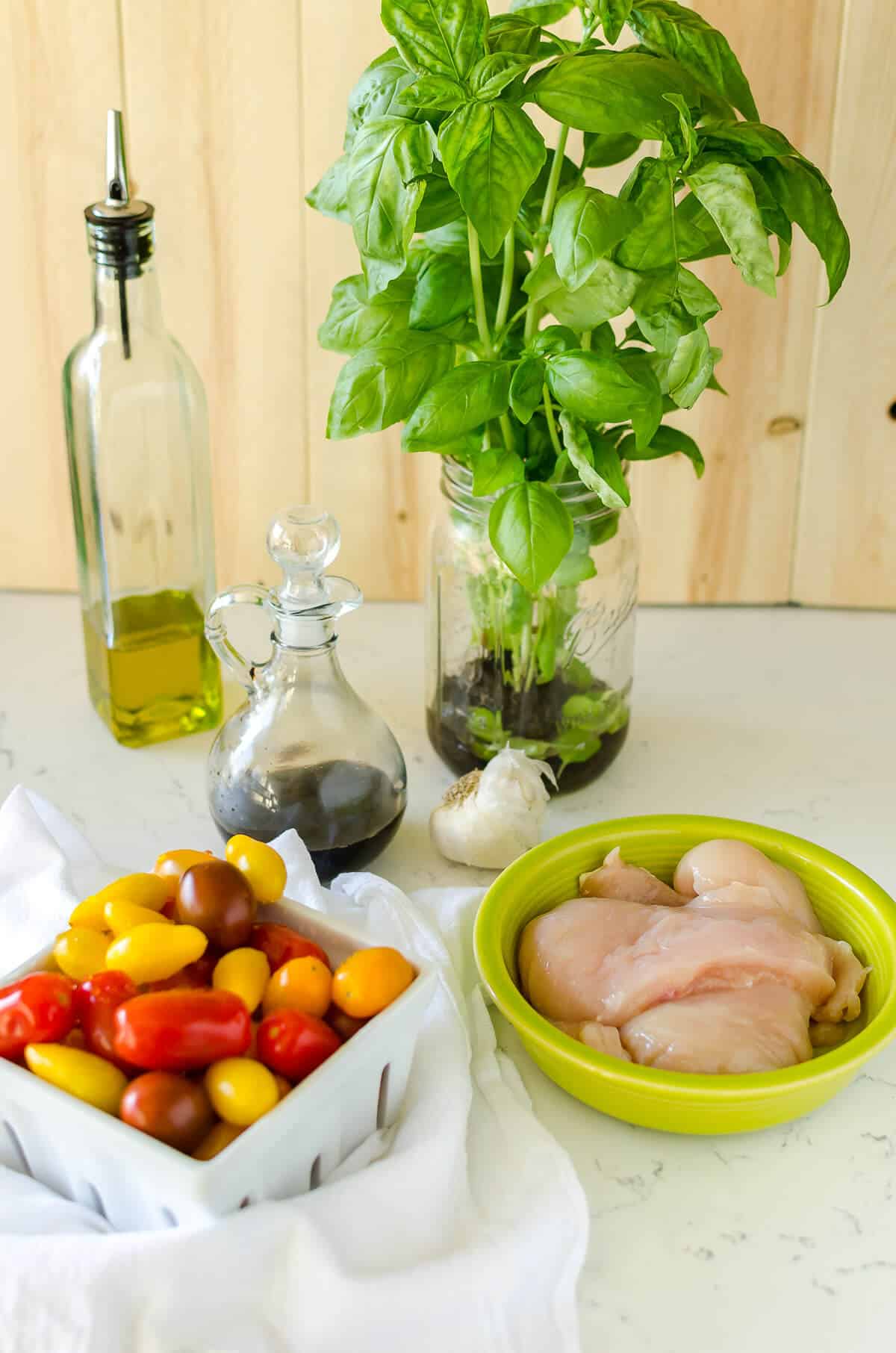raw chicken, quart of red, yellow, and orange tomatoes, olive oil dispenser, balsamic vinegar and a vase full of fresh basil for Instant Pot Bruschetta Chicken