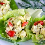 egg salad with chopped tomatoes, avocados, bacon, and blue cheese in a lettuce cup garnished with fresh dill