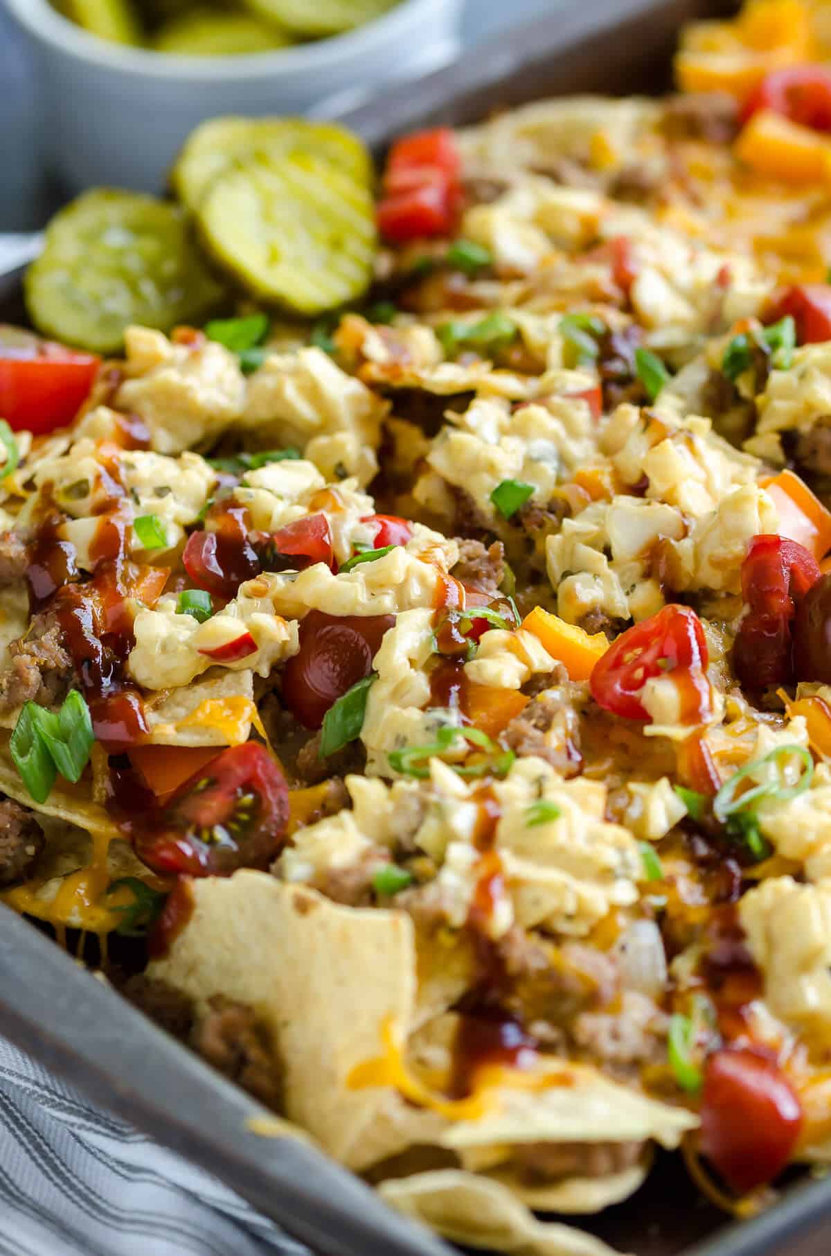 pan of bbq bacon cheeseburger nachos topped with cole slaw and barbecue sauce drizzle.