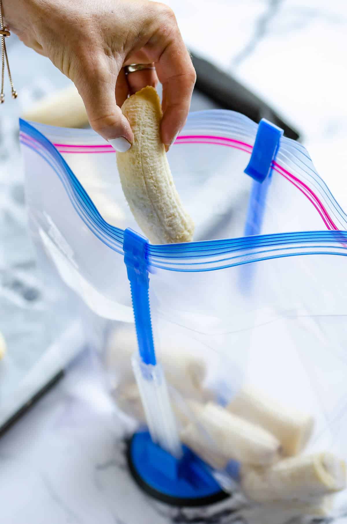 hand placing frozen banana in a gallon size zip lock bag