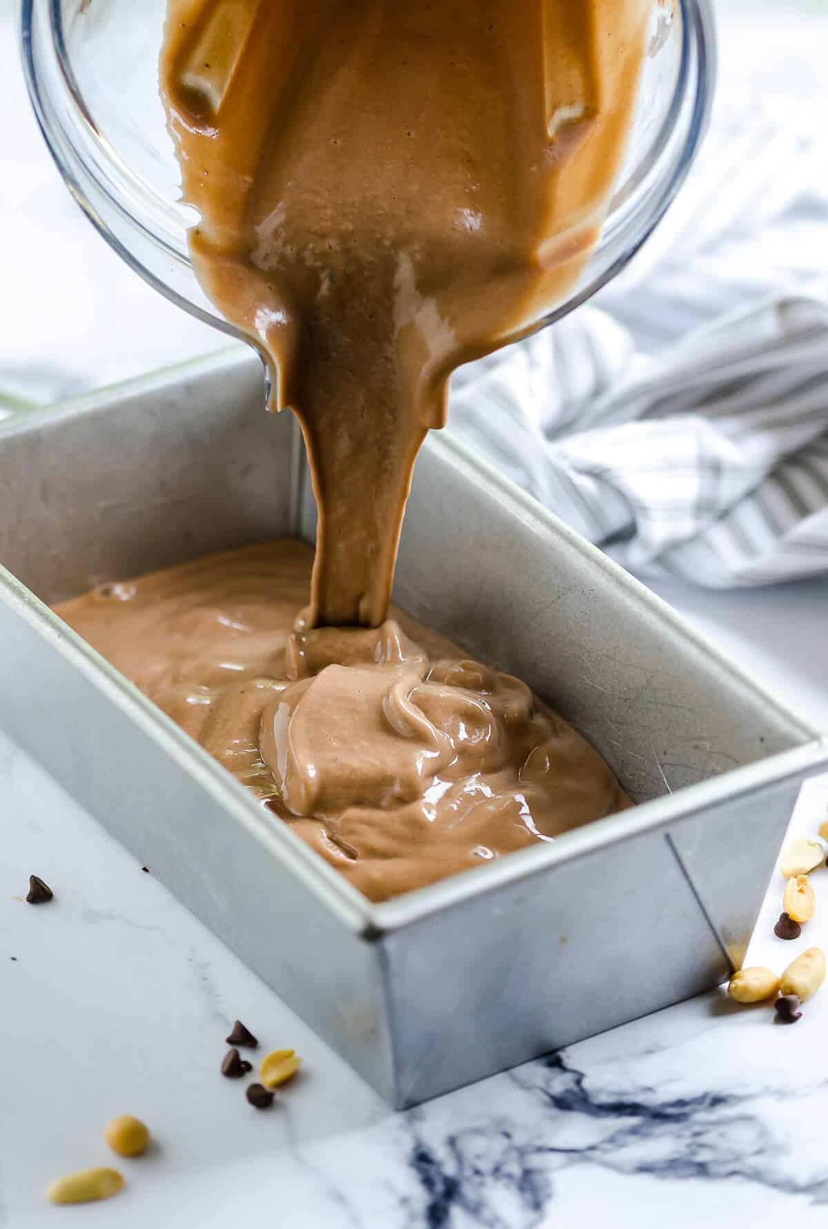 blender pouring chocolate peanut butter nice cream into a metal loaf pan