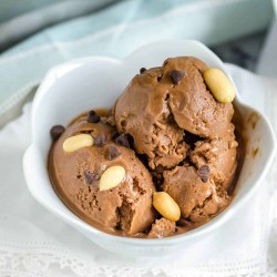 white tulip shaped bowl filled with chocolate peanut butter banana ice cream garnished with peanuts and chocolate chips