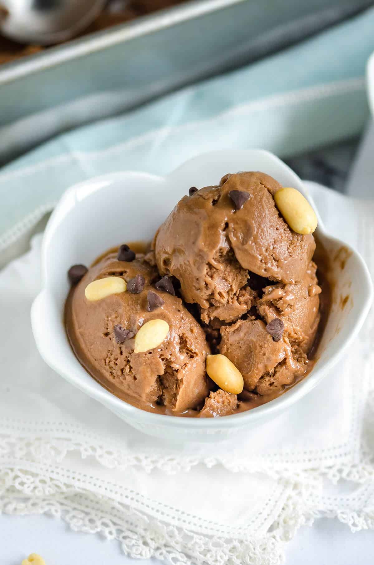 white tulip shaped bowl filled with chocolate peanut butter banana ice cream garnished with peanuts and chocolate chips
