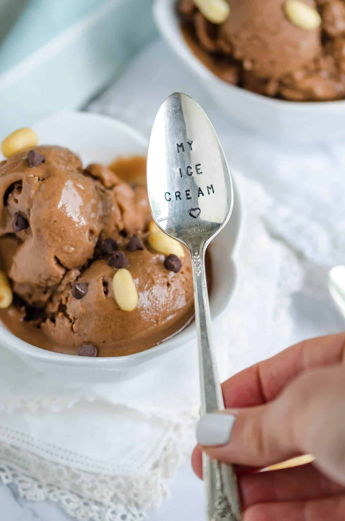 hand holding a spoon that reads 'my ice cream' with a bowl of chocolate peanut butter banana ice cream in the background.