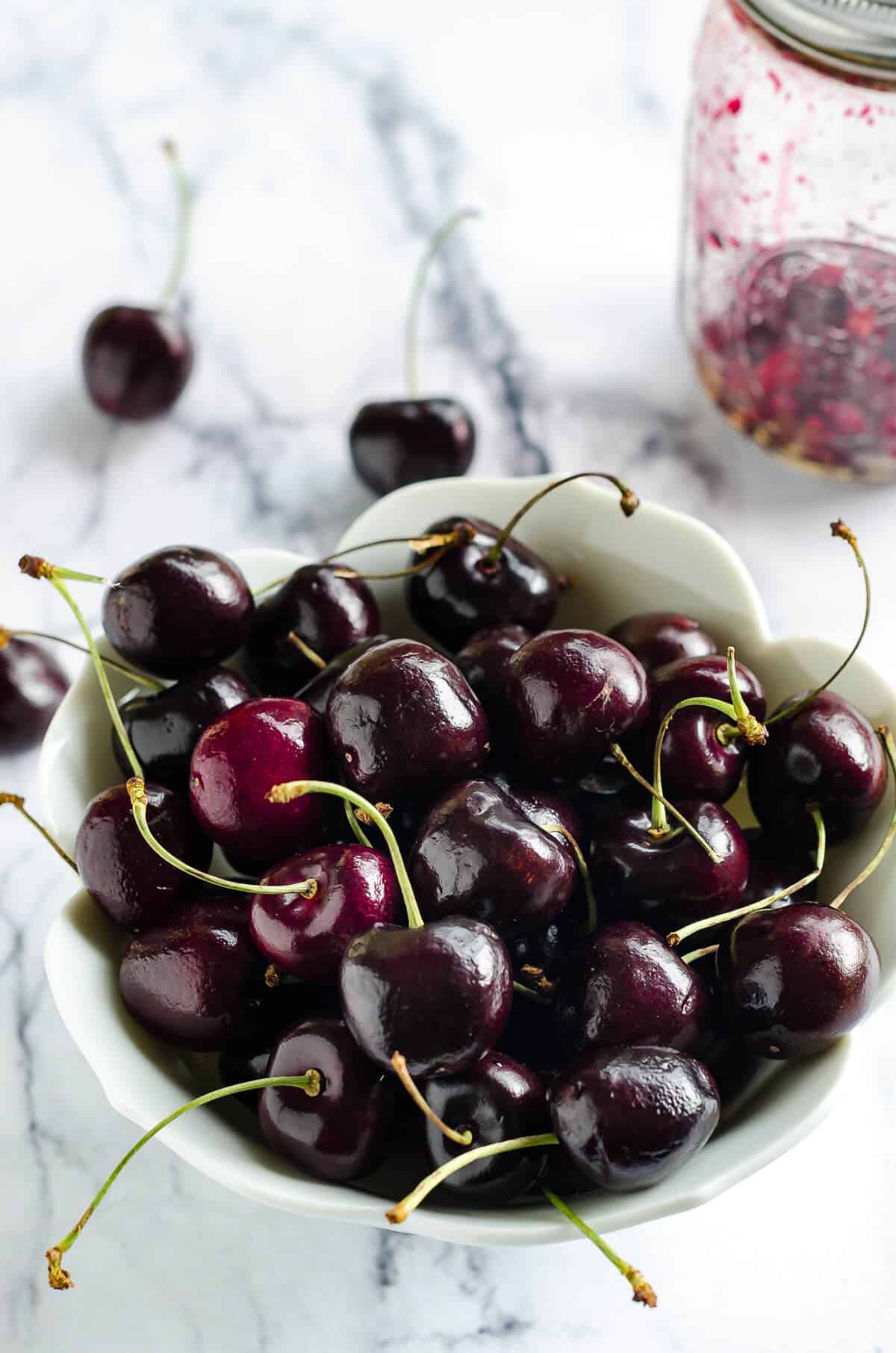 white tulip shaped bowl of fresh sweet cherries with stems