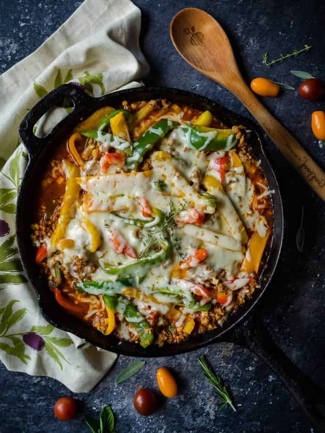 deconstructed stuffed peppers in a cast iron skillet garnished with melted cheese.