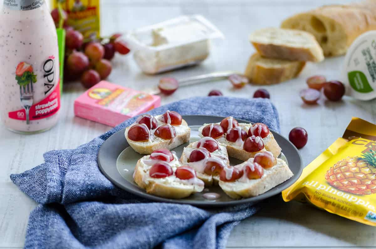 A spread of goat cheese crostini, grapes, raisins, baguette and goat cheese.