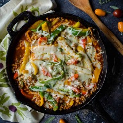 cast iron skillet of unstuffed peppers using ground turkey, colored bell peppers, cauli rice and melted cheese on top.