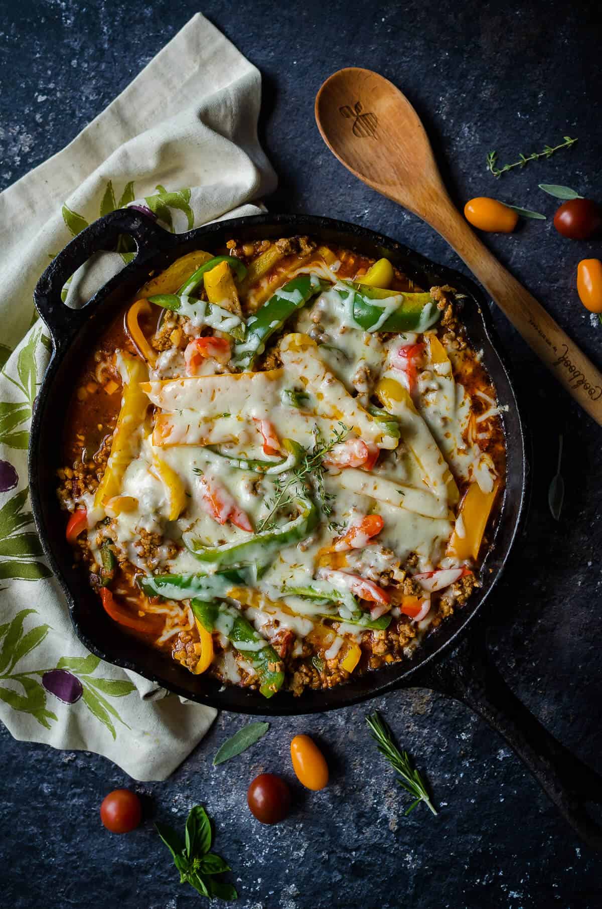 cast iron skillet of unstuffed peppers using ground turkey, colored bell peppers, cauli rice and melted cheese on top.