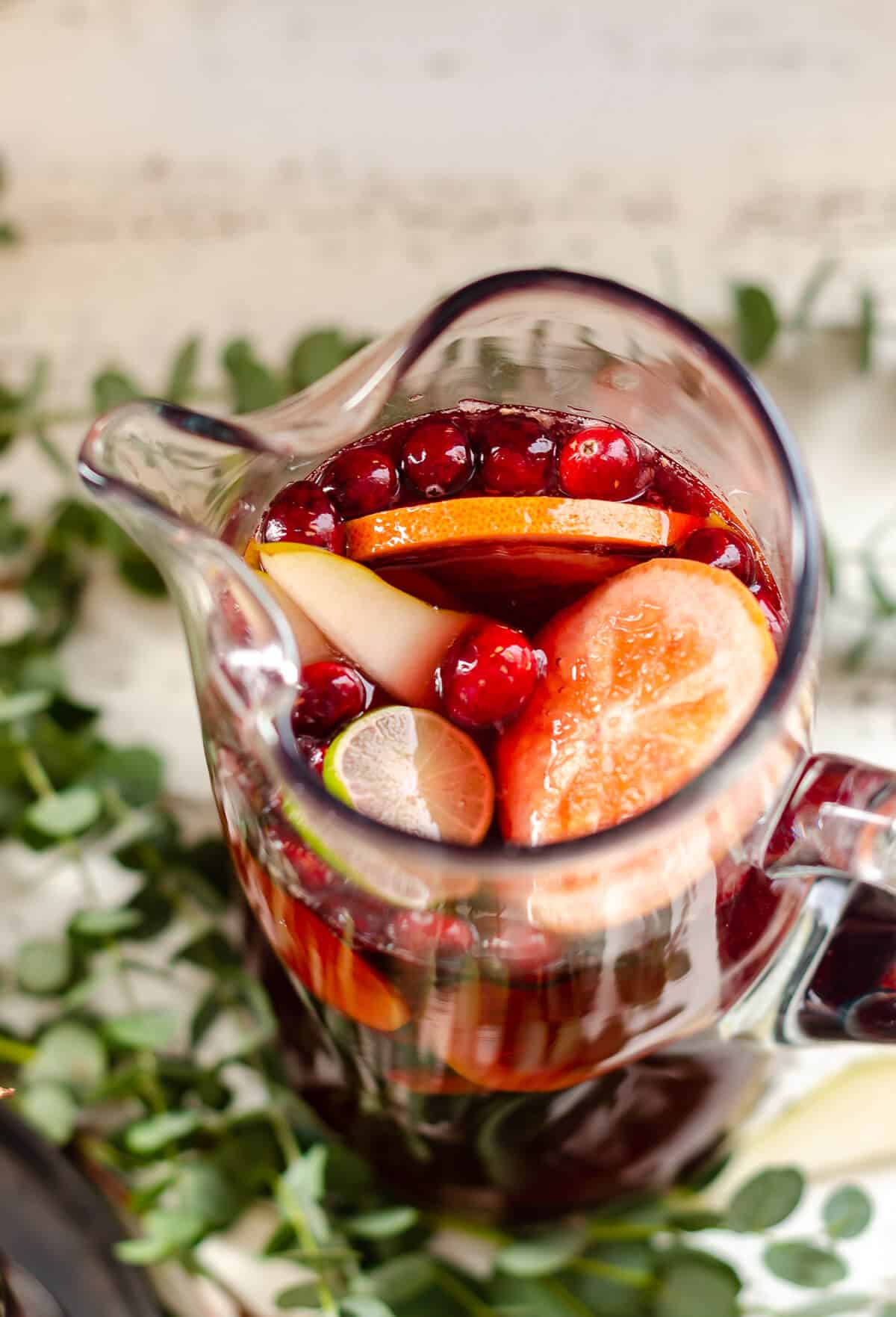 overhead view of a pitcher filled with red Sangria Mocktail, grapefruit, limes, pears and cranberries