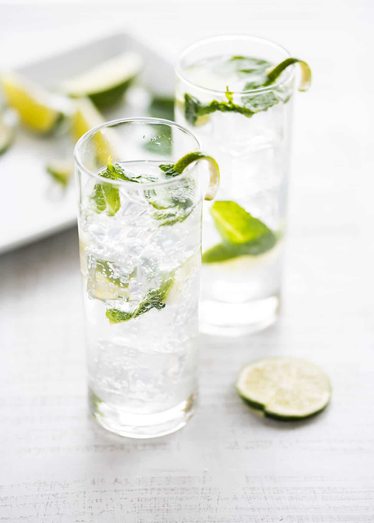 two mojito mocktails in clear glasses with fresh mint and lime