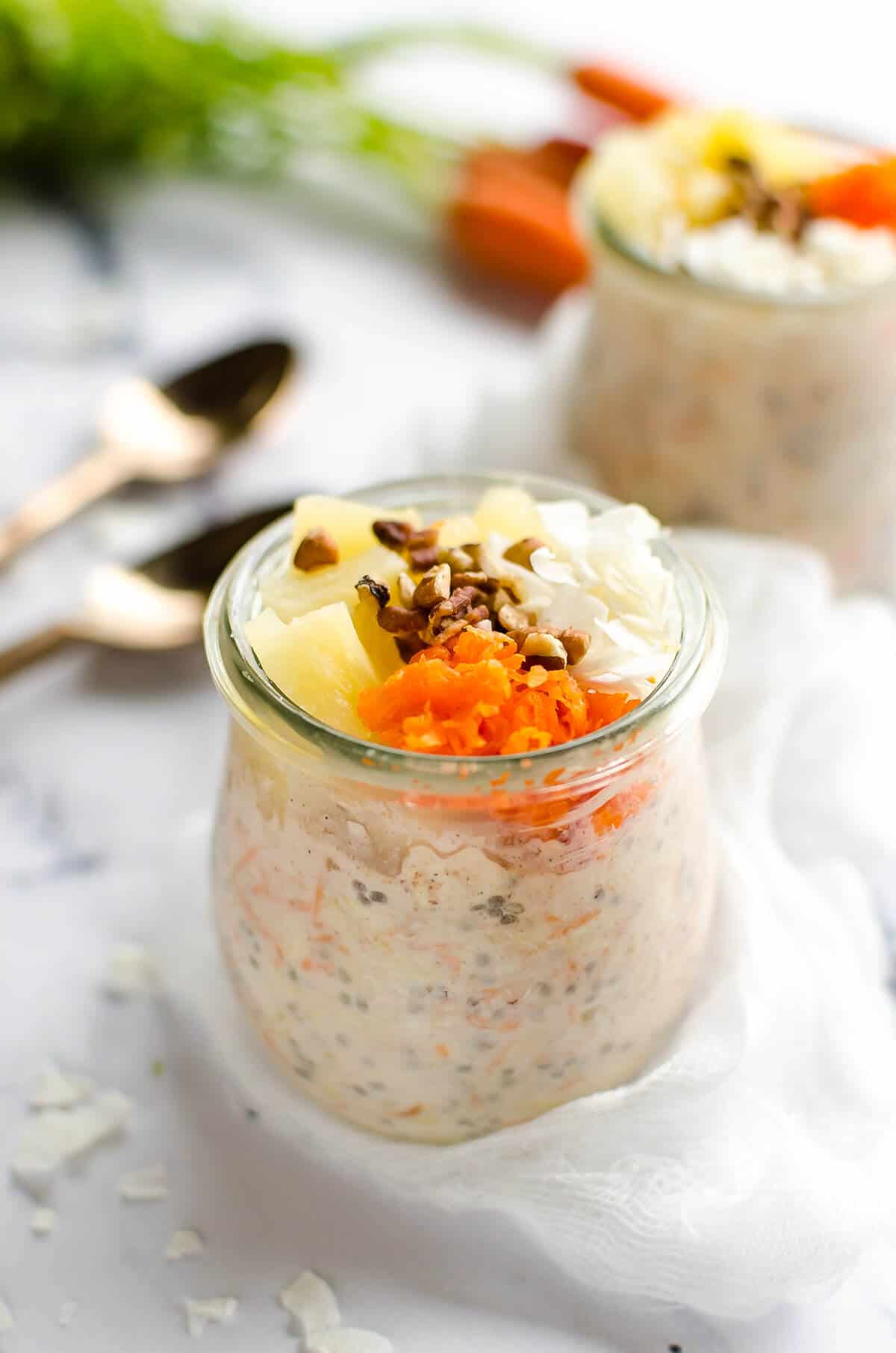 jar of carrot cake overnight oats topped with grated carrots, pineapple, coconut and pecans