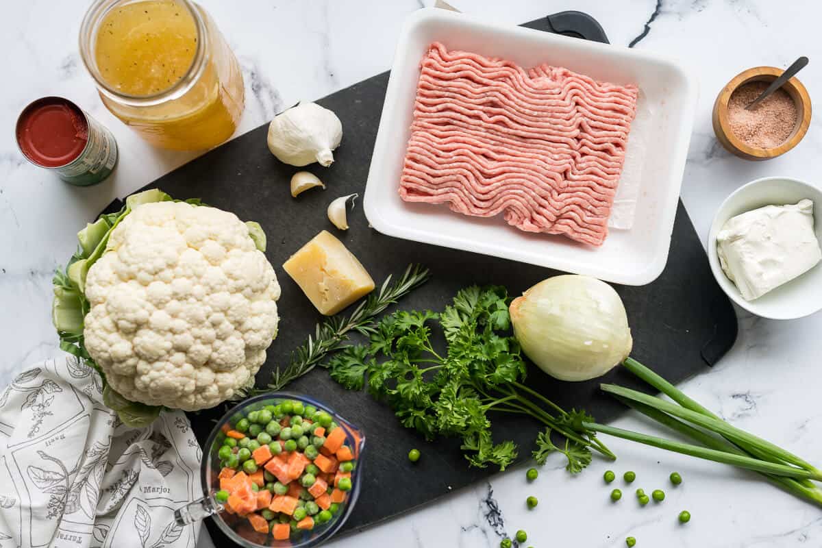 ingredients for low carb cottage pie, ground turkey, cauliflower, onion, garlic, peas, carrots, cheese, broth, tomato paste