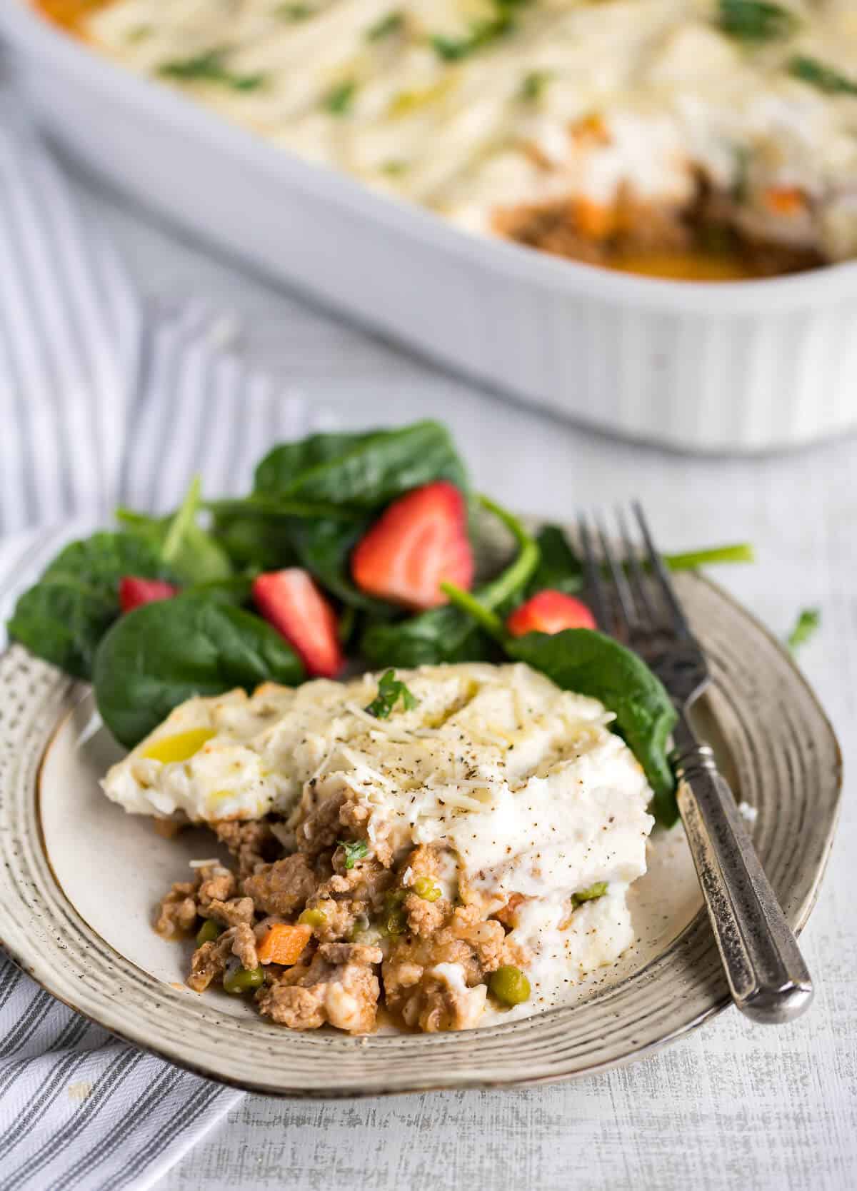plate with helping of cottage pie made with ground turkey and cauli mash, with a side salad