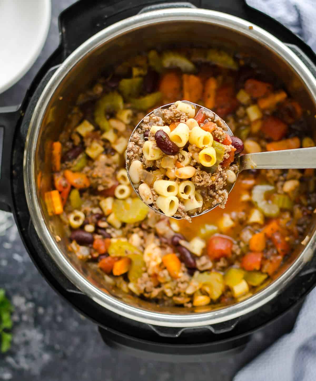 soup ladle full of pasta fagioli soup above the pot