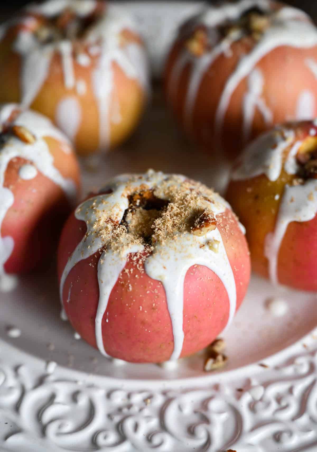 whole baked apple with yogurt sauce drizzled on top and chopped pecans