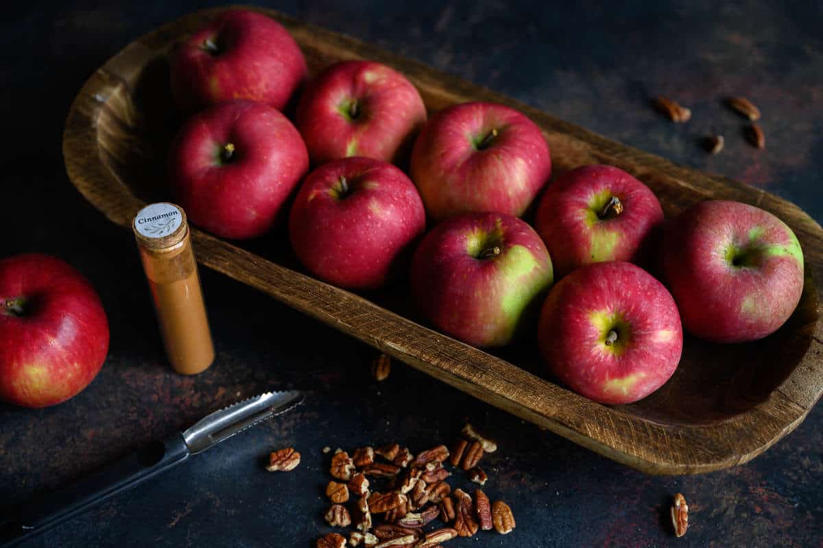 Fresh apples on long platter, pecans, and cinnamon