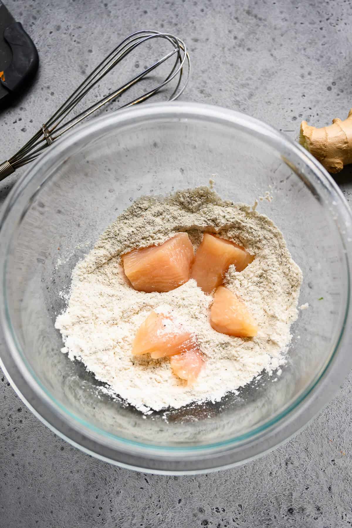 chunks of raw chicken being dredged flour