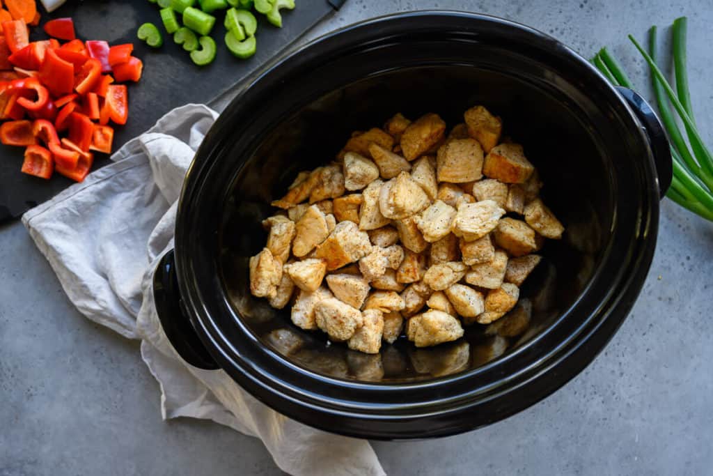 browned pieces of chicken in a crockpot