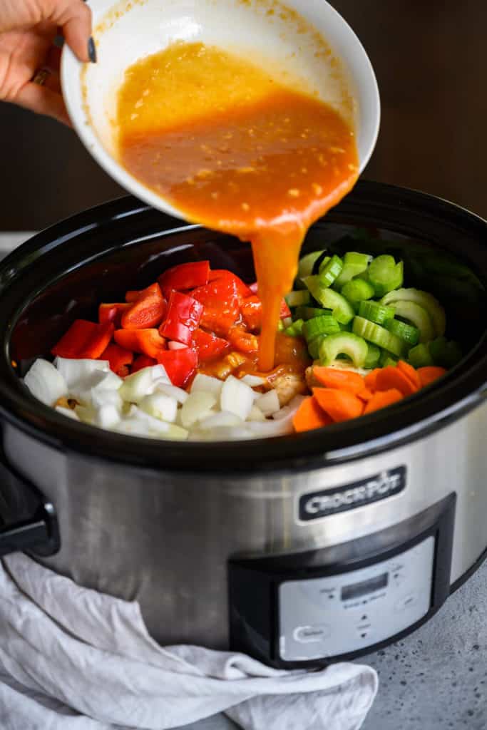 orange sauce being poured into a crockpot
