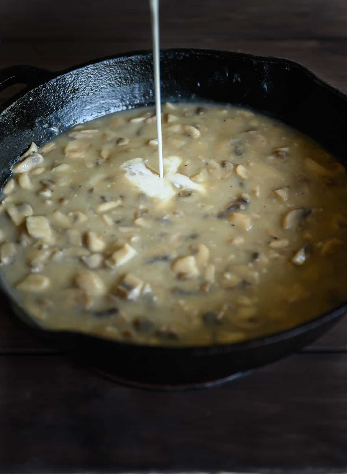 heavy cream being poured into mushroom sauce