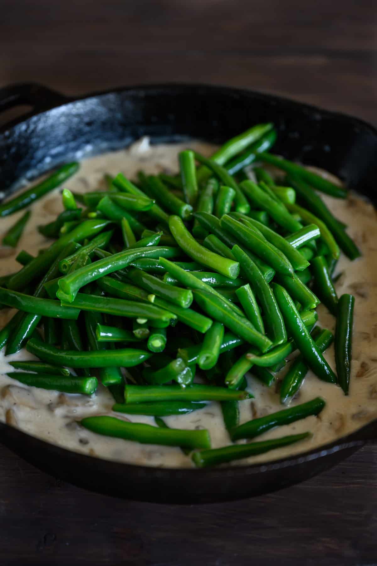 green beans on mushroom sauce in a cast iron skillet