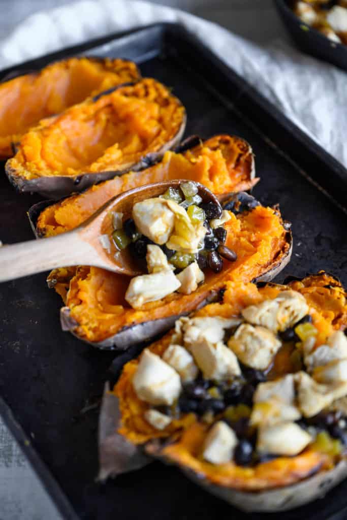cooked sweet potatoes being filled with chicken enchilada filling