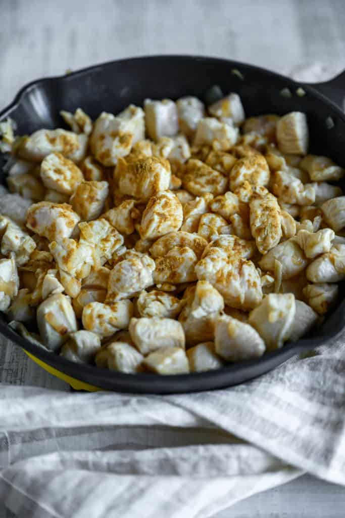 pan full of bite size chicken seasoned with cumin