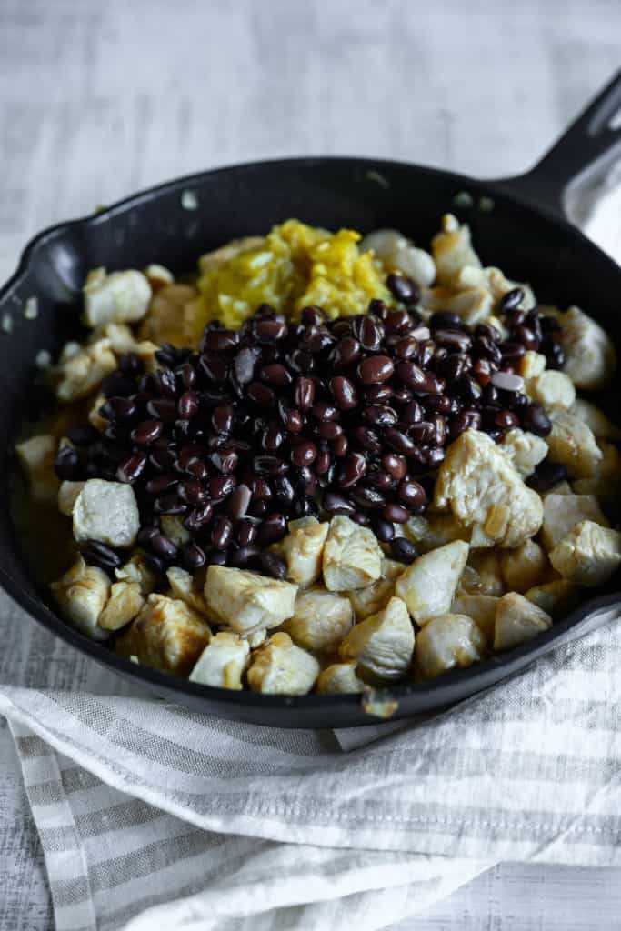 skillet filled with chicken, black beens and green chilis