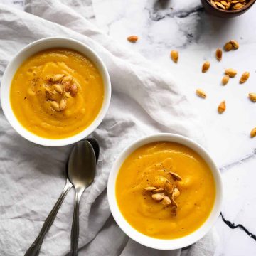 Two bowls of roasted butternut squash soup garnished with squash seeds