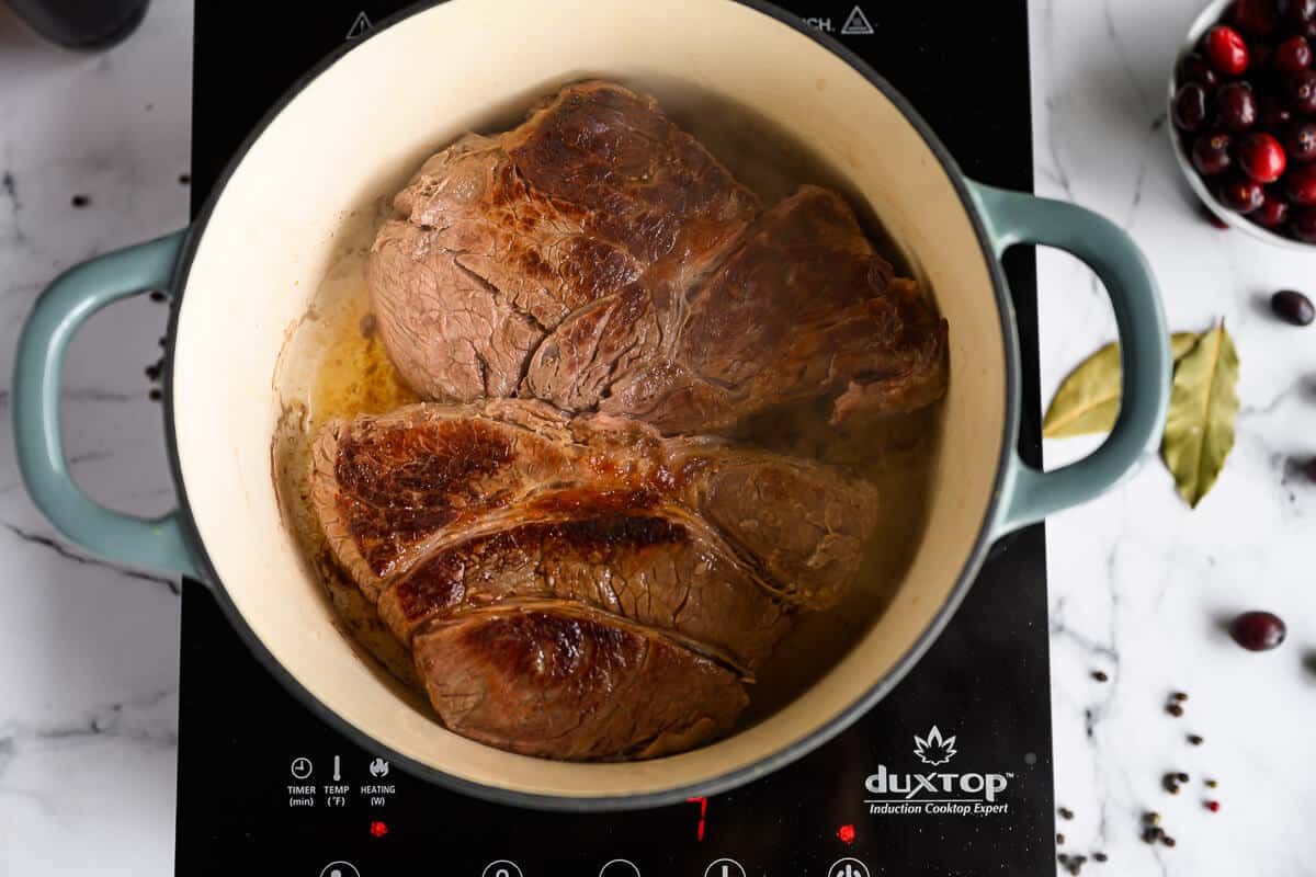 chuck roast being seared in a dutch oven