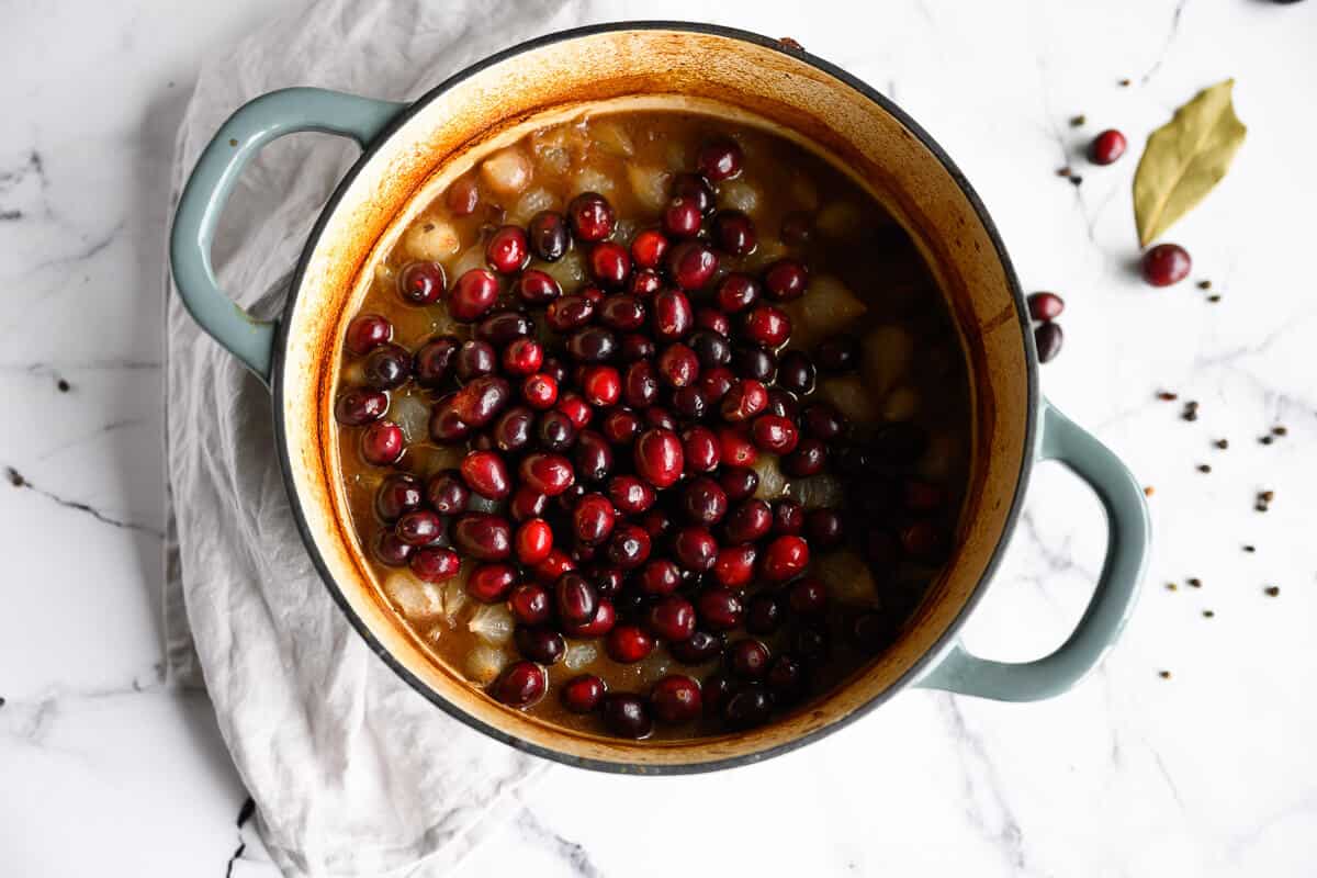 braised beef topped with cranberries in a dutch oven