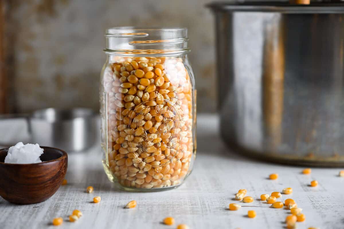 jar of popcorn kernels next to whirly pop popcorn popper.