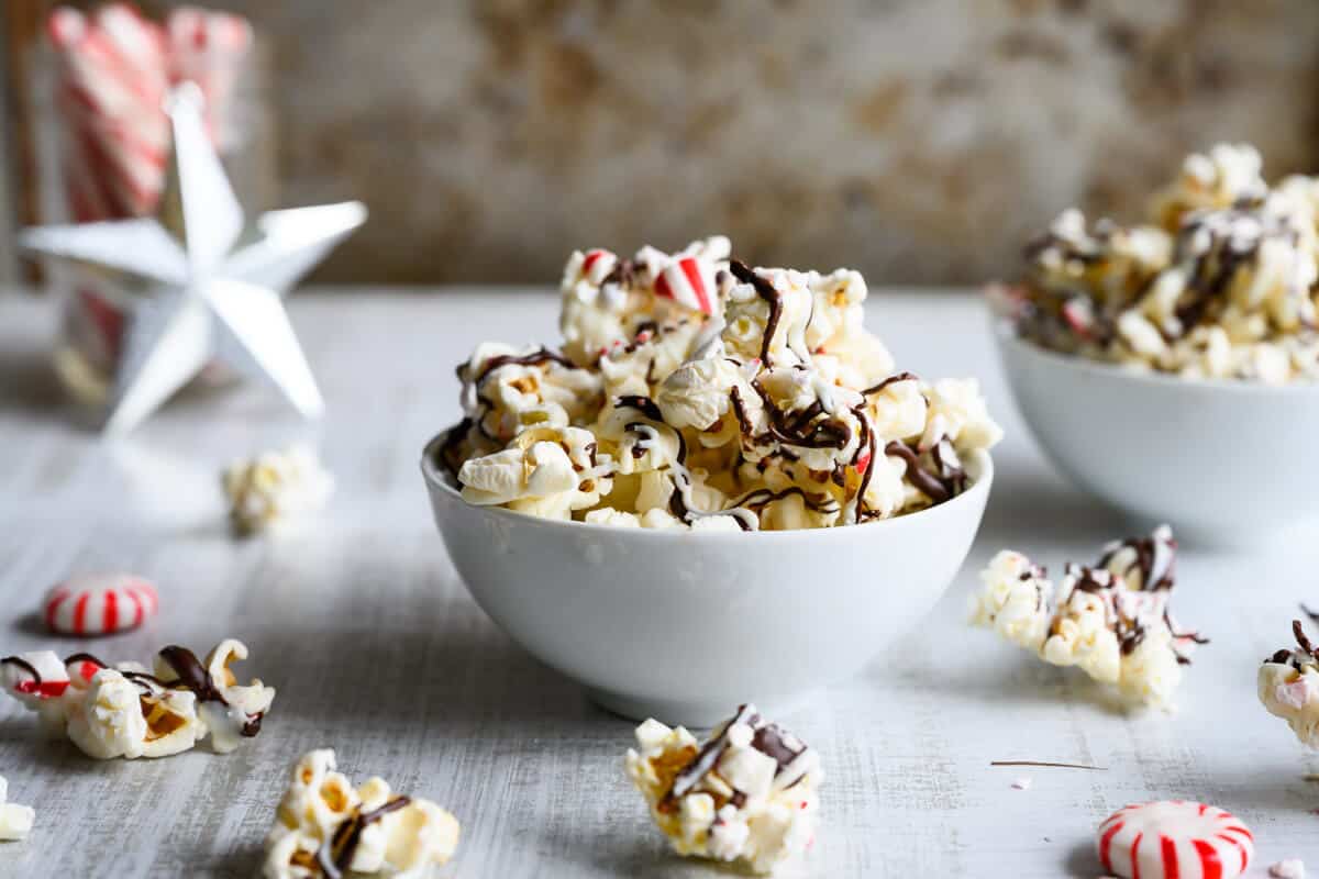 bowl of popcorn drizzled with white and dark chocolate and crushed peppermint
