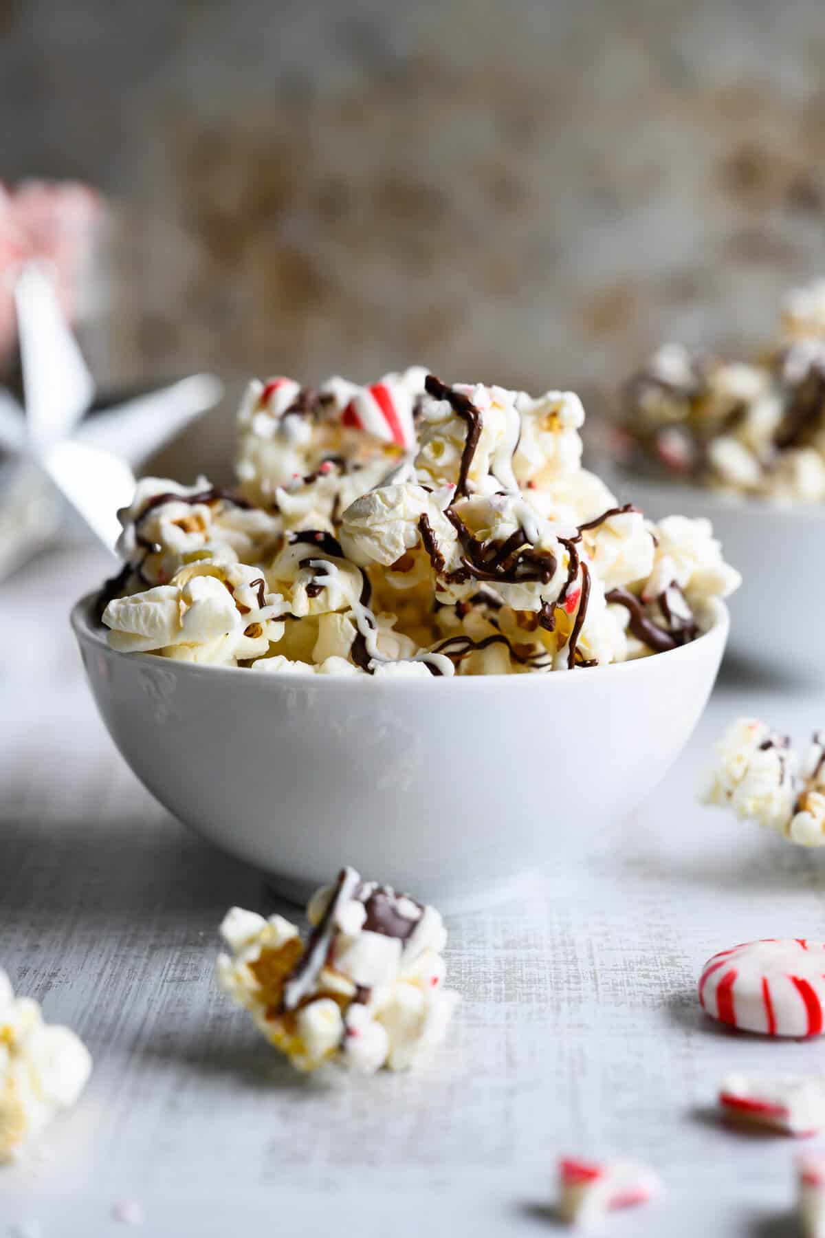 bowl of  popcorn drizzled with dark and white chocolate and crushed peppermints
