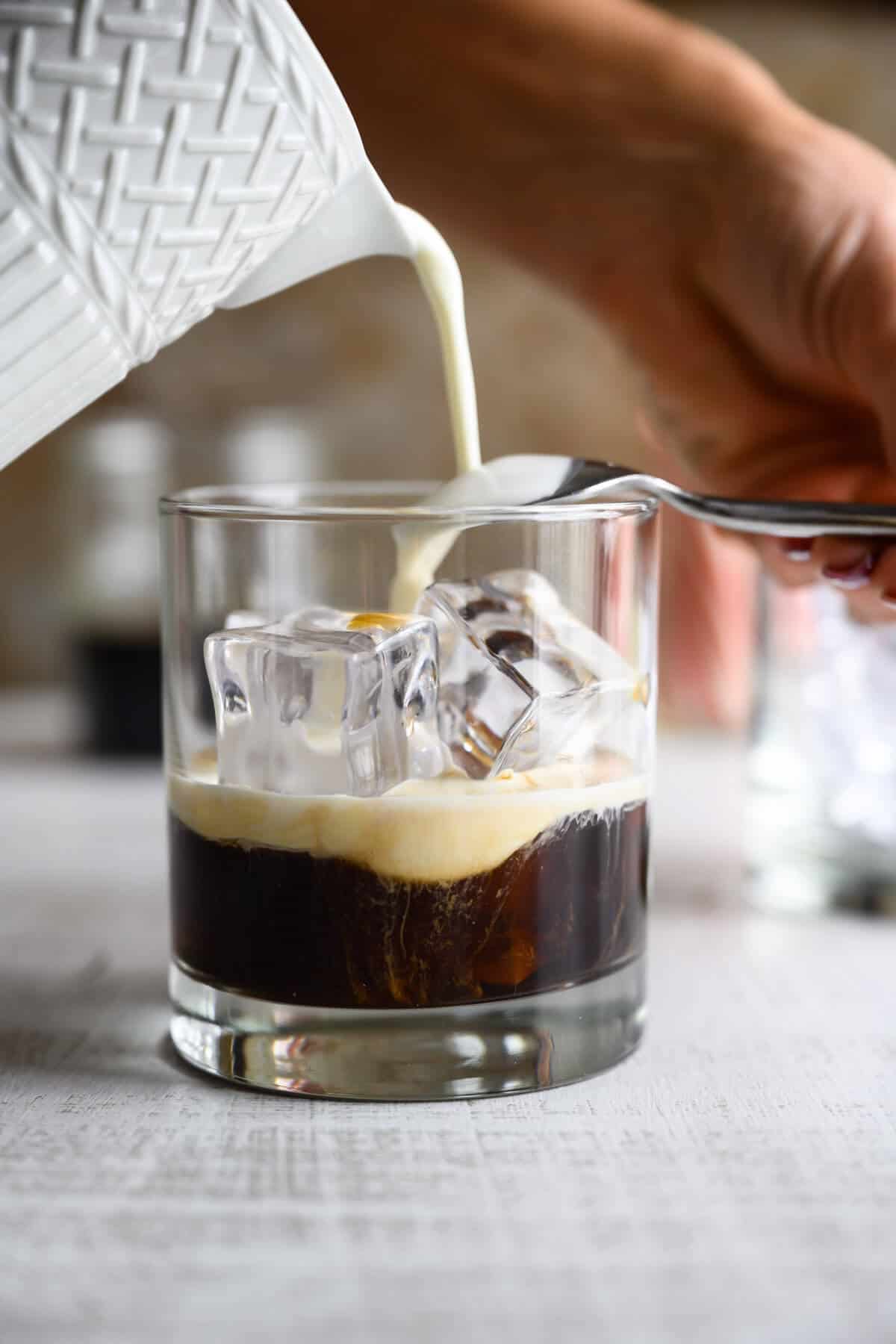 cream being floated over coffee in a white russian