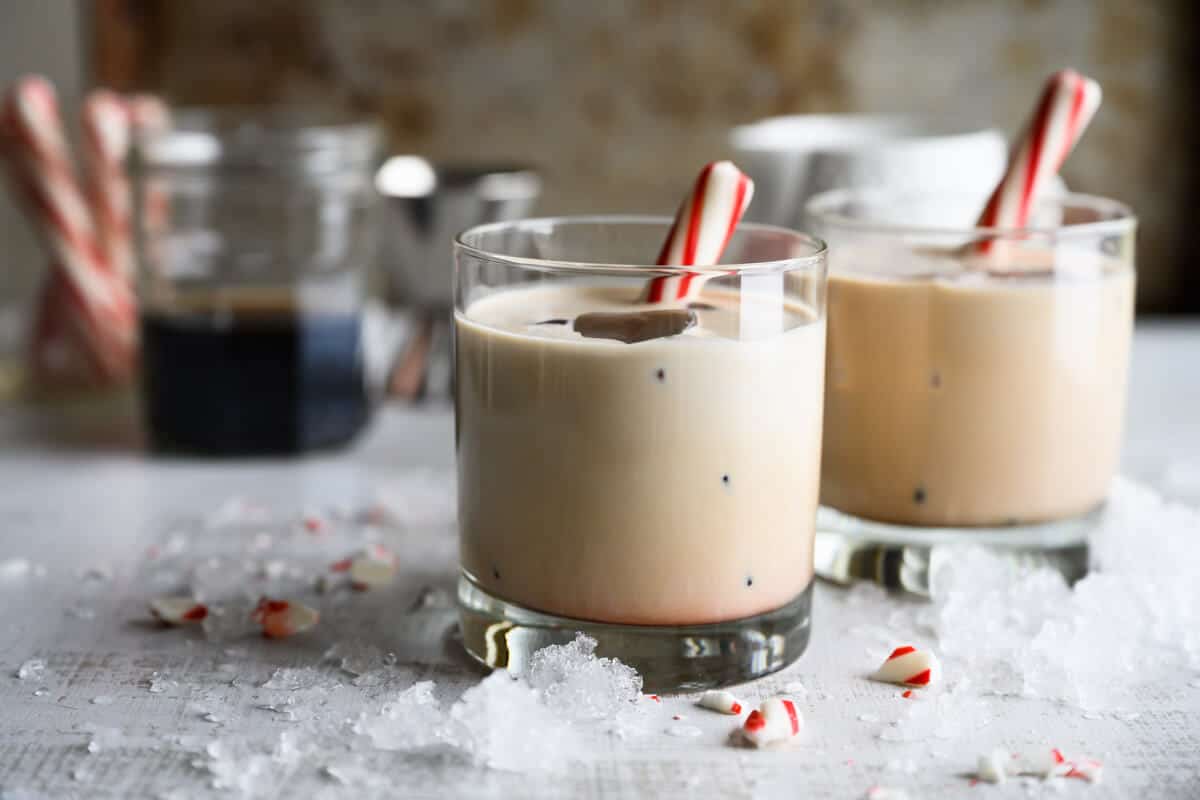 two peppermint white russian mocktails garnished with peppermint sticks