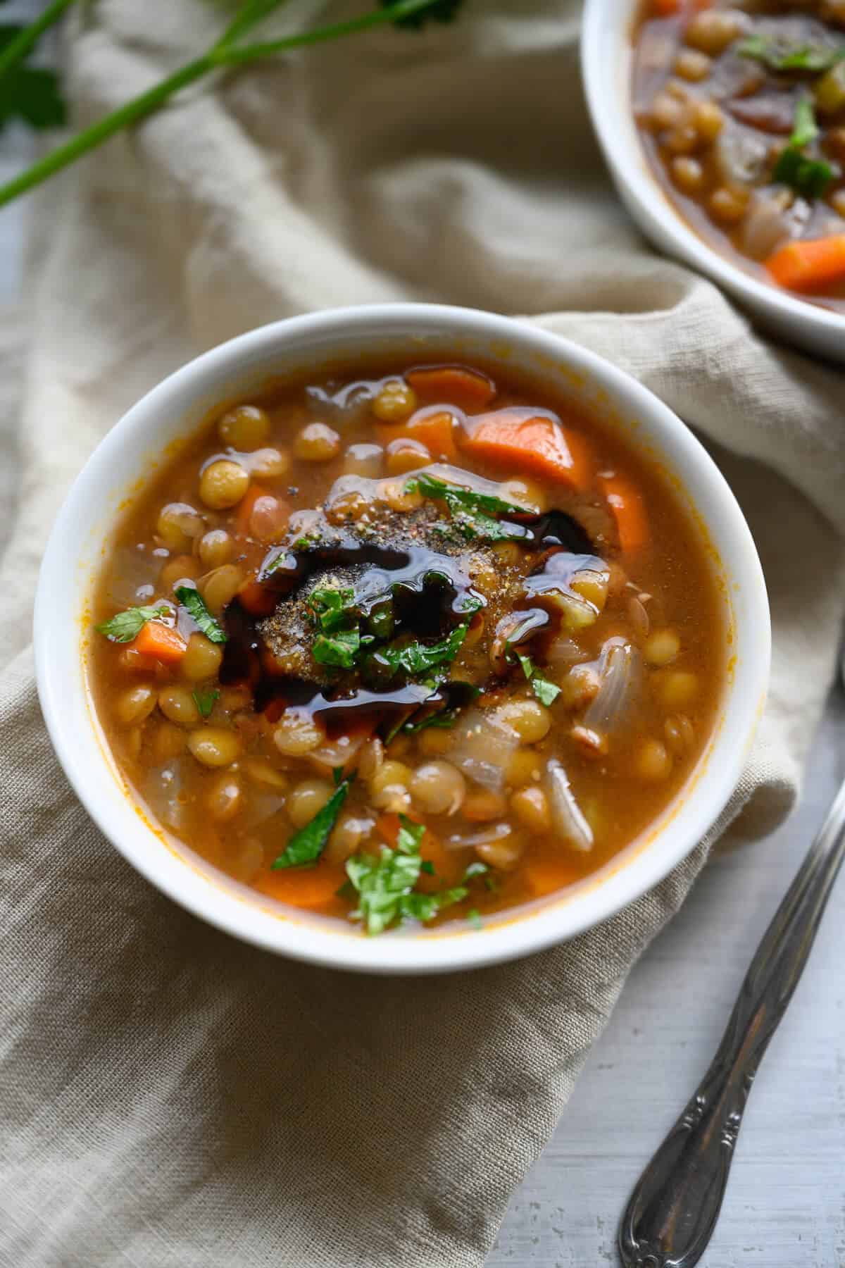 bowl of lentil soup garnished with balsamic reduction, parsley and cracked pepper