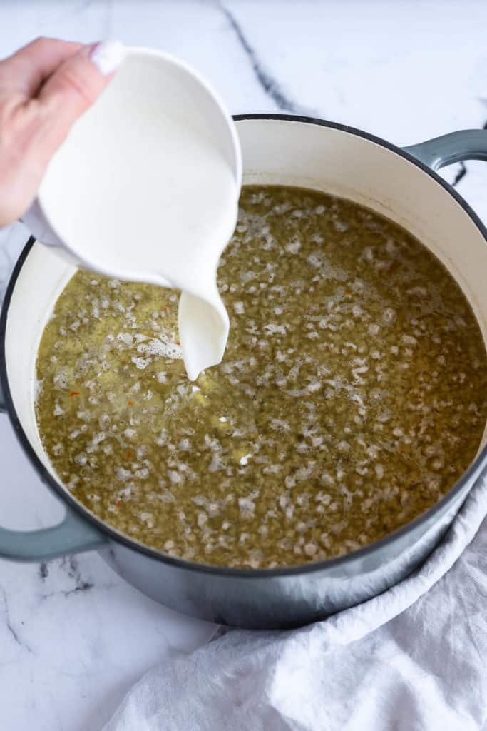 heavy cream being poured into sausage soup